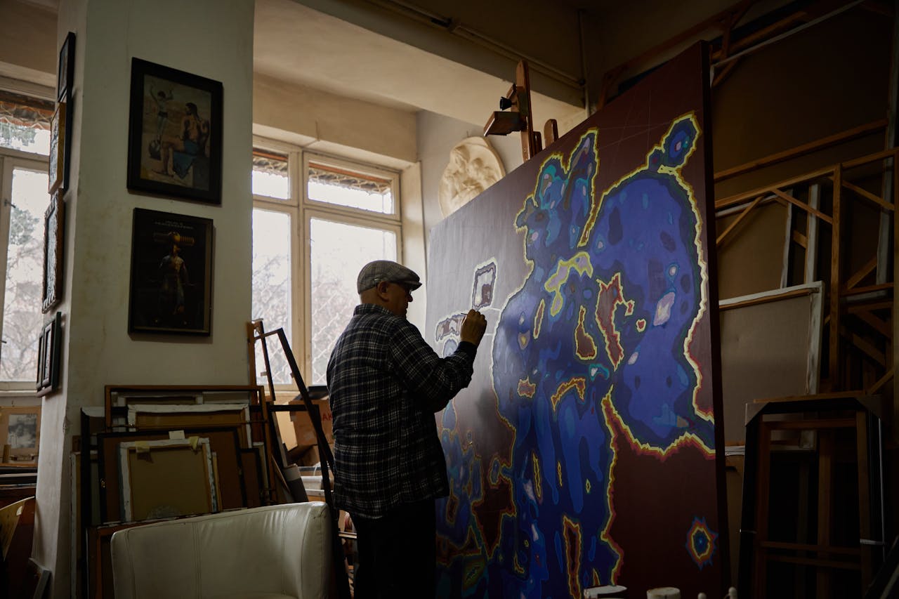 A senior artist paints a colorful abstract canvas in a sunlit studio in Tashkent, Uzbekistan.